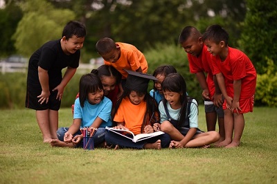group-of-children-lying-reading-on-grass-field.jpg